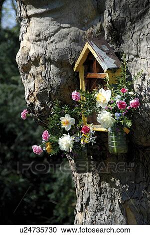 Stock Image - Birdhouse with flowers in a tree. Fotosearch