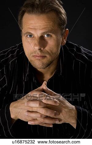 Stock Image - Close-up shot of man with hands folded. Fotosearch