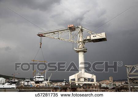 Stock Photography - Crane lifting a boat in the harbor. Fotosearch