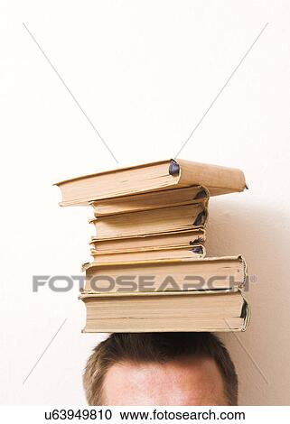 Stock Image - Man balancing books on his head. Fotosearch