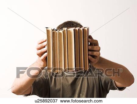 Stock Photo - Man holding books in front of face. Fotosearch