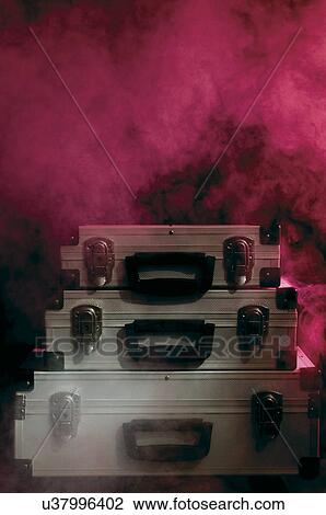 Stock Image - Three silver briefcases stacked with red background. Fotosearch