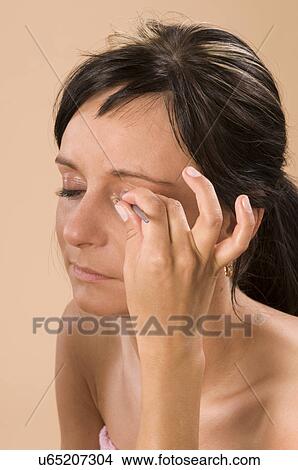 Picture - Woman applying eye make-up. Fotosearch