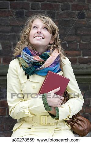 Stock Photo - Woman in coat holding book. Fotosearch