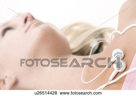 Woman laying down with earbuds on chest View Large Photo Image Stock Photo - Woman laying down with earbuds on chest. Fotosearch
