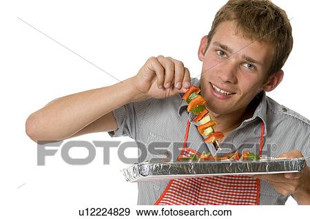 Young man holding shish kabobs View Large Photo Image Stock Photo - Young man holding shish kabobs. Fotosearch