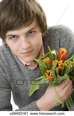 Stock Image - Young man holding tulips. Fotosearch