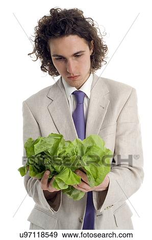 Stock Photo - Young man in suit holding green leaf lettuce. Fotosearch