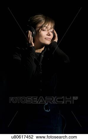 Young woman listening to headphones with eyes closed View Large Photo Image Stock Image - Young woman listening to headphones with eyes closed. Fotosearch