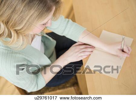 Stock Photo - Blond woman sitting down and writting letter. Fotosearch