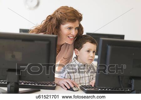 Stock Image - boy (6-7) and teacher using computer. Fotosearch