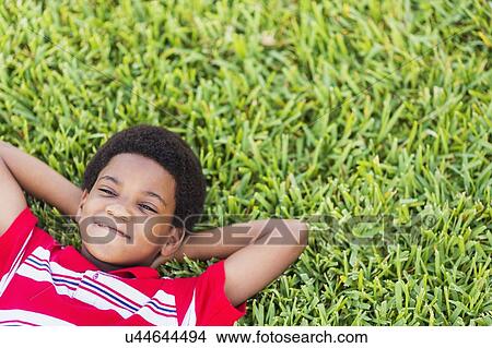 boy (6-7) lying on grass View Large Photo Image Picture - boy (6-7) lying on grass. Fotosearch