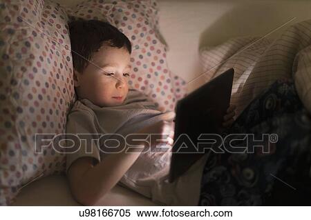 boy (6-7) using digital tablet in bed View Large Photo Image Stock Photography - boy (6-7) using digital tablet in bed. Fotosearch