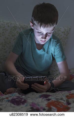 boy (8-9) using digital tablet in bed View Large Photo Image Stock Photo - boy (8-9) using digital tablet in bed. Fotosearch