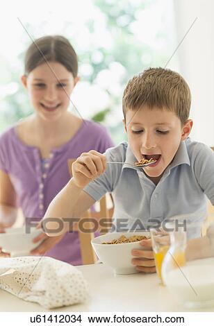 Boy and girl (8-9, 10-11) eating cereals View Large Photo Image Picture - Boy and girl (8-9, 10-11) eating cereals. Fotosearch