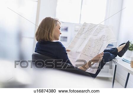 Business woman looking at blueprint in office View Large Photo Image Stock Image - Business woman looking at blueprint in office. Fotosearch