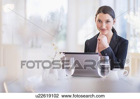 Businesswoman working on laptop in restaurant View Large Photo Image Stock Image - Businesswoman working on laptop in restaurant. Fotosearch