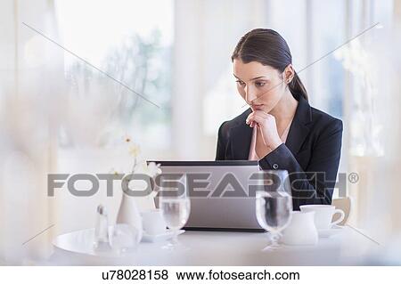 Businesswoman working on laptop in restaurant View Large Photo Image Stock Photo - Businesswoman working on laptop in restaurant. Fotosearch