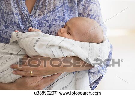 Stock Photo - Close up of baby boy (2-5 months) sleeping in mother's arms. Fotosearch