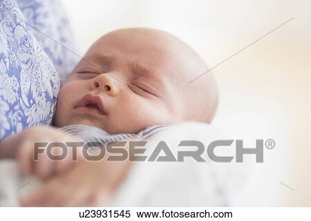 Stock Photography - Close up of baby boy (2-5 months) sleeping in mother's arms. Fotosearch