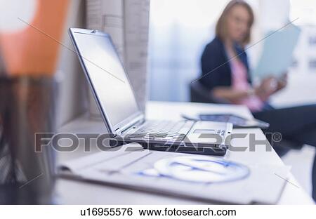 Close up of laptop and digital tablet on desk, woman in background View Large Photo Image Stock Photograph - Close up of laptop and digital tablet on desk, woman in background. Fotosearch