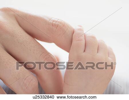 Stock Image - Close up of mother's hand touching baby boy's(2-5 months) foot. Fotosearch