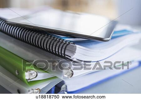 Stock Image - Close up of stack of notebooks with digital tablet on top. Fotosearch