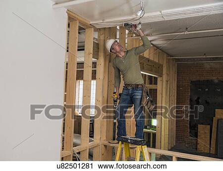 Construction worker drilling in ceiling inside new structure View Large Photo Image Stock Image - Construction worker drilling in ceiling inside new structure. Fotosearch