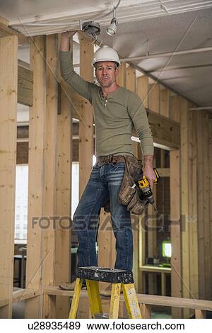 Construction worker drilling in ceiling inside new structure View Large Photo Image Stock Photo - Construction worker drilling in ceiling inside new structure. Fotosearch