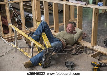 Stock Image - Construction worker falling of ladder inside new structure. Fotosearch