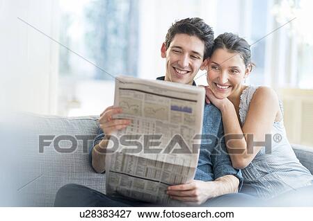 Couple reading newspaper on sofa View Large Photo Image Stock Photo - Couple reading newspaper on sofa. Fotosearch