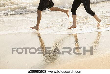 Couple running on beach, low section View Large Photo Image Stock Photo - Couple running on beach, low section. Fotosearch