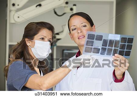 Dentist and assistant looking at x-ray View Large Photo Image Stock Image - Dentist and assistant looking at x-ray. Fotosearch