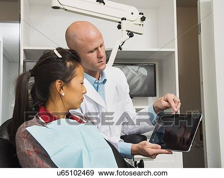 Stock Photo - Dentist holding digital tablet with patient's x-ray. Fotosearch