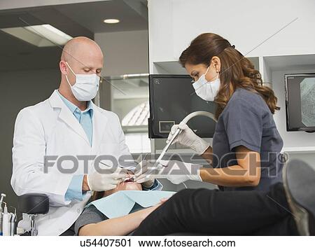 Stock Image - Dentist operation on patient. Fotosearch