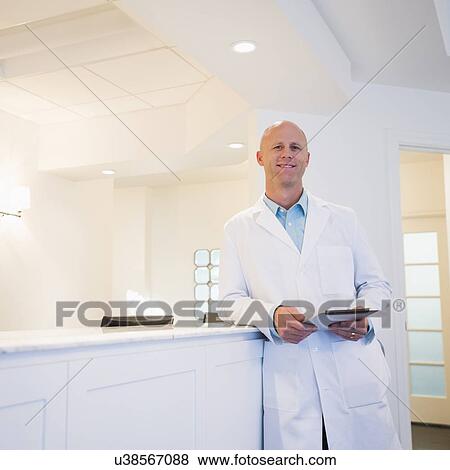 Stock Photo - Doctor leaning against reception desk. Fotosearch