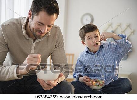 Father and son (8-9) eating breakfast cereal View Large Photo Image Stock Photo - Father and son (8-9) eating breakfast cereal. Fotosearch