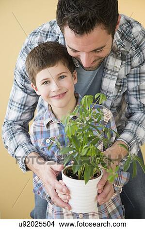 Picture - Father and son (8-9) holding potted plant . Fotosearch