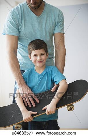 Father and son (8-9) holding skateboard View Large Photo Image Stock Photo - Father and son (8-9) holding skateboard . Fotosearch