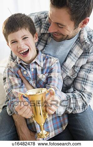 Father and son (8-9) holding trophy View Large Photo Image Stock Photo - Father and son (8-9) holding trophy. Fotosearch