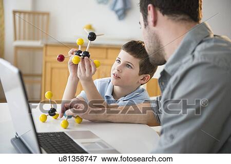 Stock Photo - Father and son (8-9) looking at molecule model stack. Fotosearch
