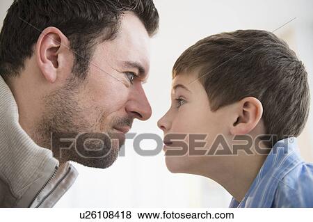 Stock Photo - Father and son (8-9) staring at each other. Fotosearch