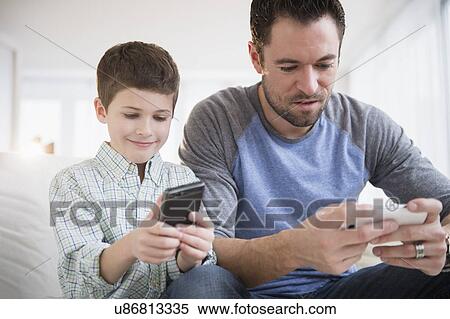 Father and son (8-9) using mobile phone View Large Photo Image Stock Photography - Father and son (8-9) using mobile phone. Fotosearch