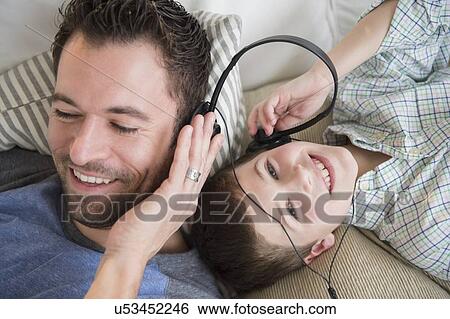 Stock Photograph - Father listening to music with son (8-9). Fotosearch