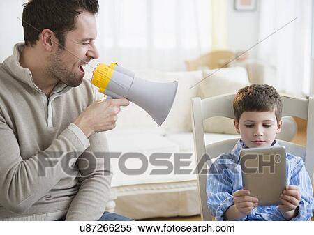 Stock Photography - Father yelling into megaphone to discipline son (8-9). Fotosearch