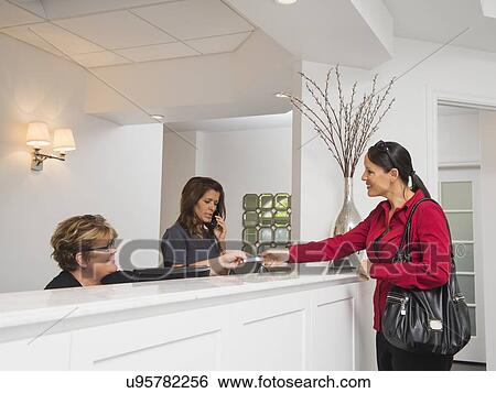 Stock Photograph - Female patient at doctor's office front desk. Fotosearch
