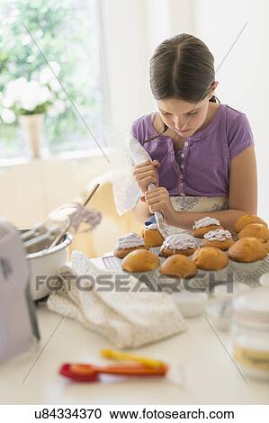 Stock Image - girl (10-11) decorating cakes. Fotosearch