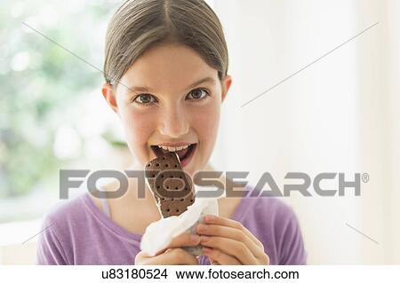 Picture - girl (10-11) eating ice cream sandwich. Fotosearch