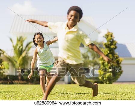 girl (8-9) and boy (6-7) playing on front yard View Large Photo Image Picture - girl (8-9) and boy (6-7) playing on front yard. Fotosearch