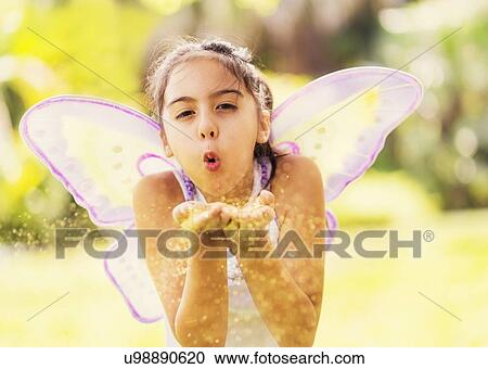 Stock Image - girl (8-9) blowing fairy dust. Fotosearch